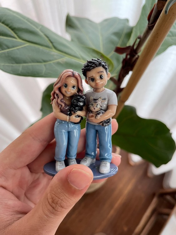 Figurine of a couple, each holding one of their two cats