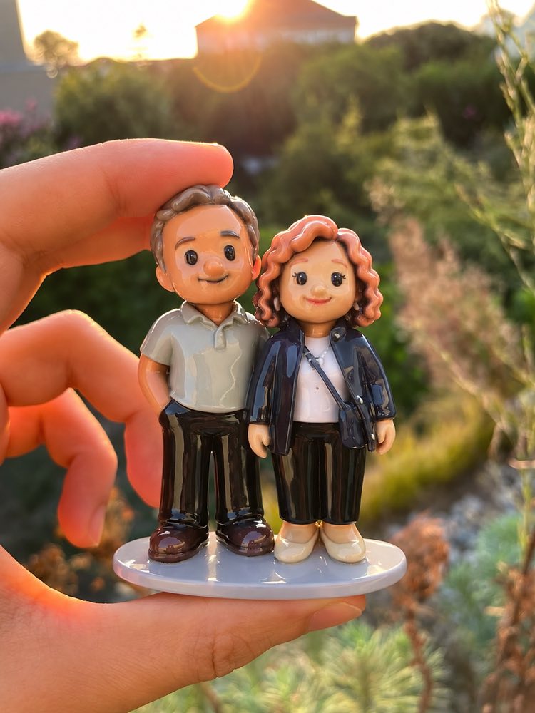 Couple figurine standing side by side, held up against a garden at sunset