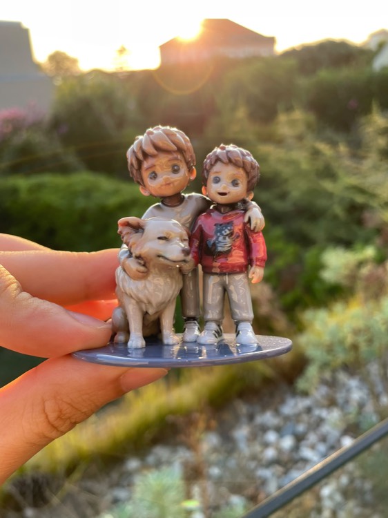 Figurine of two brothers with their dog, held up against a sunset