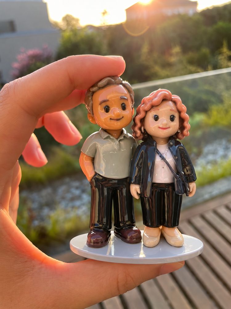 The finished couple figurine held in one hand on a balcony at sunset